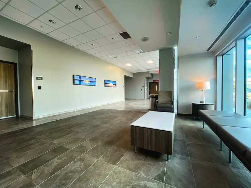 Quiet medical office lobby with tile flooring, bench seating and tall windows