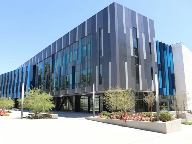 Modern multi-story office building with blue and gray cladding and a landscaped plaza